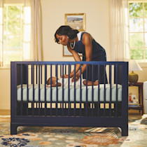 Parent tending baby in crib, navy blue Posey crib