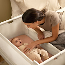 Person placing a baby into the SnuzPod5 bassinet