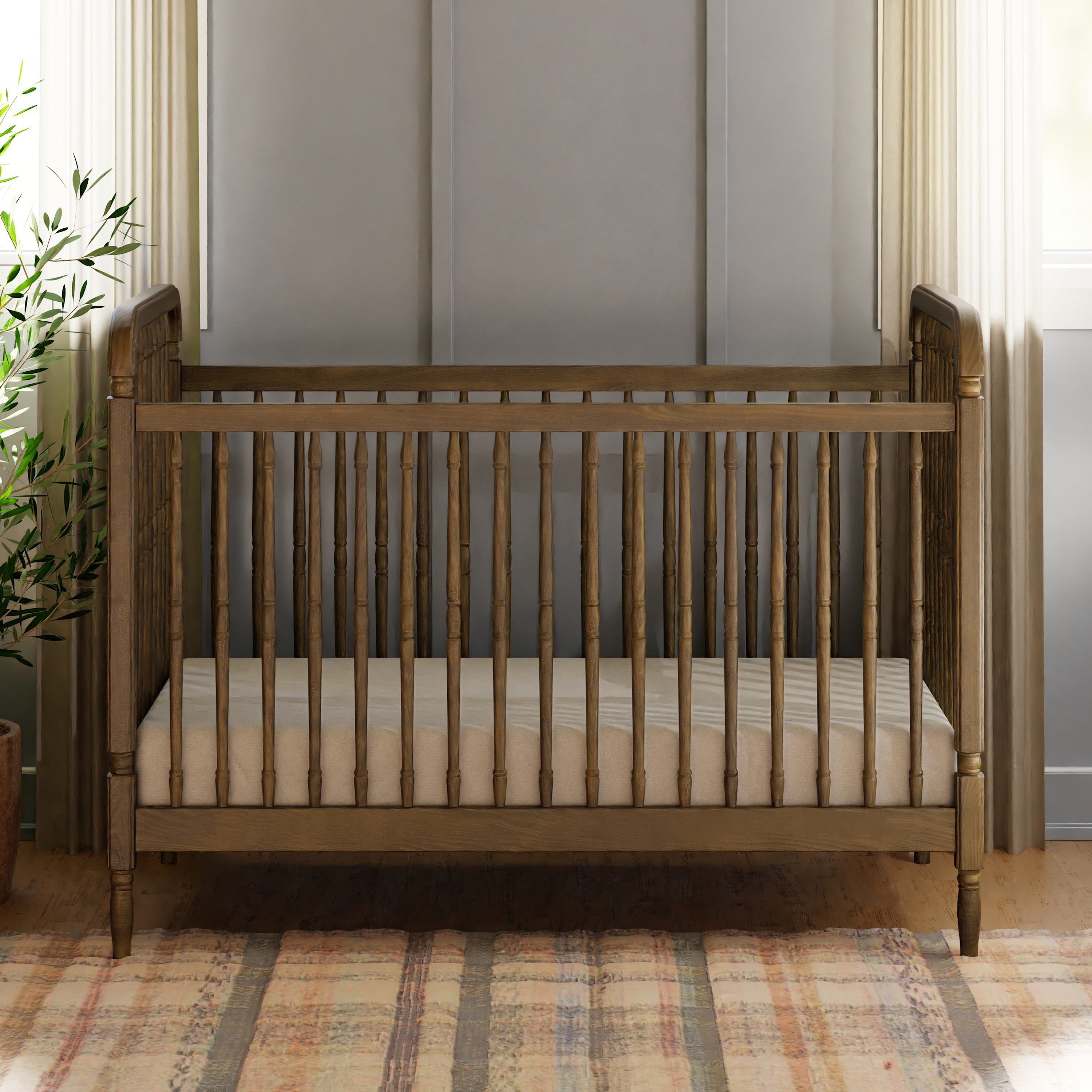 Wooden spindle crib in a nursery with a patterned rug.