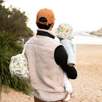 Adult carrying child in booster chair with patterned cover
