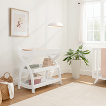 White changing table in a bright room with a plant and rug