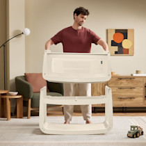 Man assembling the SnuzPod5 bassinet in a living room