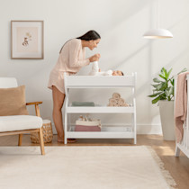 Mother with baby at a white changing table in nursery