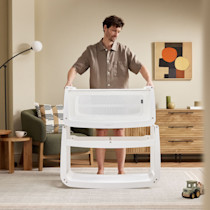 Adult assembling SnuzPod5 bassinet frame in living room
