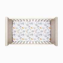Top-down view of crib with printed bedding and fitted sheet