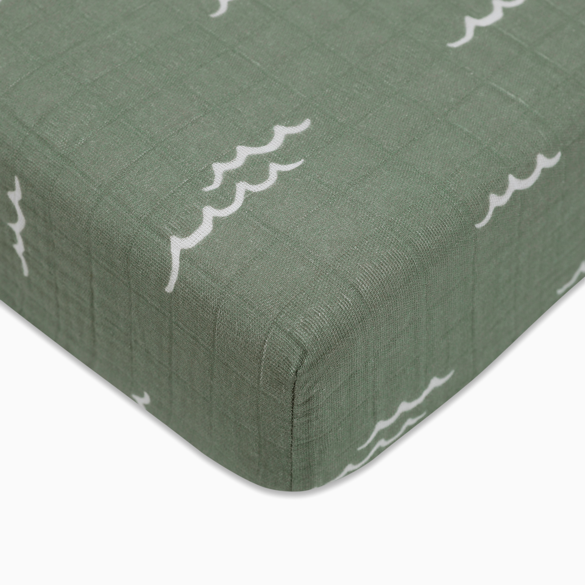 Close-up of a crib sheet fabric with green wavy water pattern.
