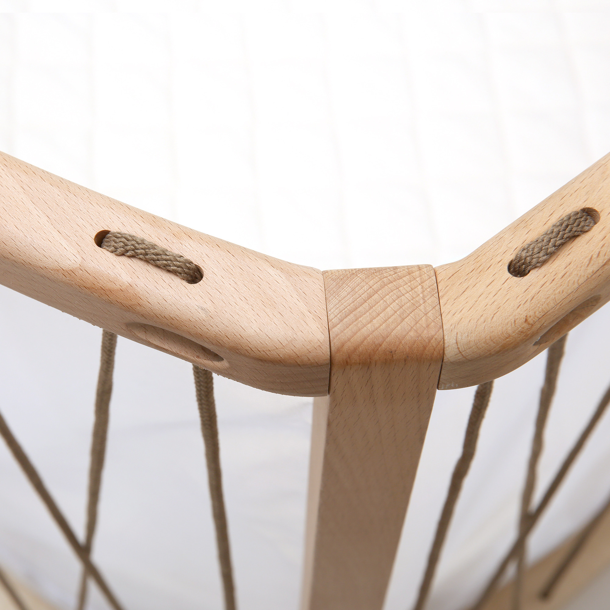 Close-up of wooden bed frame corner with rope detailing.