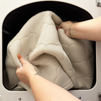 hands folding/cramming mattress into washing machine