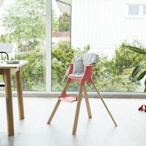 Pink wooden high chair in a bright room.