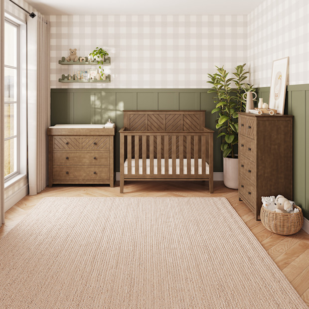 Bedroom styled with wooden furniture, crib, and plants.