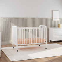 Crib in a nursery with rug and dresser