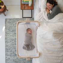 Baby sleeping swaddled in the Halo Bassinest bedside sleeper