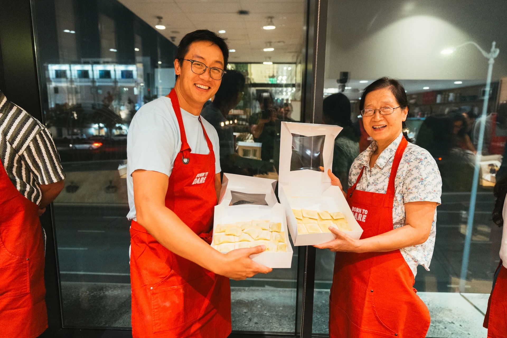 Two participants to the TUDOR at Eataly event holding their creations, fresh raviolis in a box.