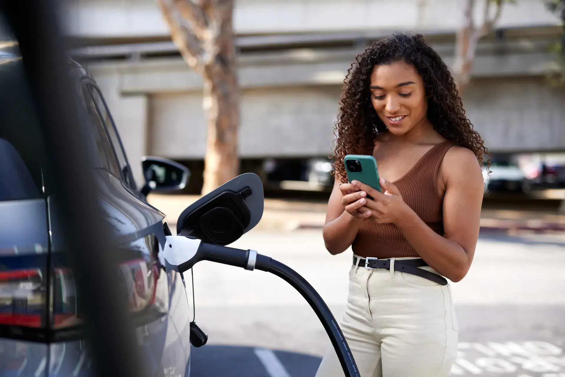 Woman checks her phone as her electric car charges