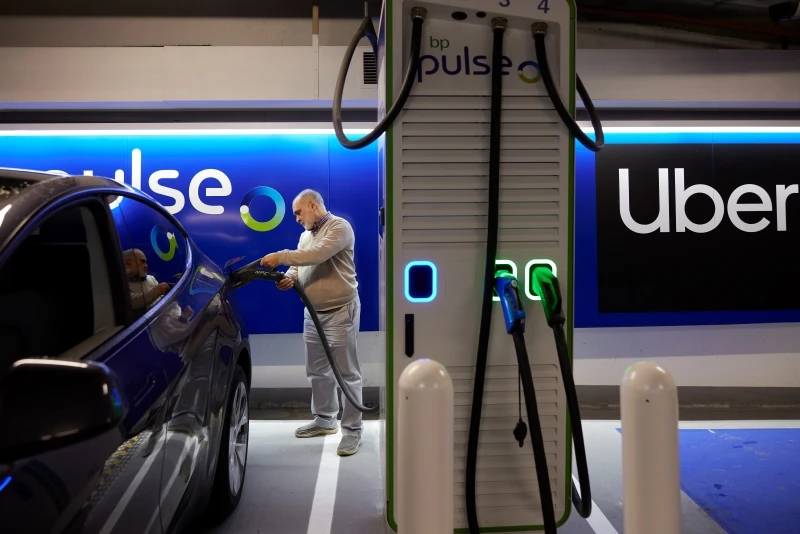 A male Uber driver at the Pimlico Q-Park Gigahub charging his car with a bp pulse charger