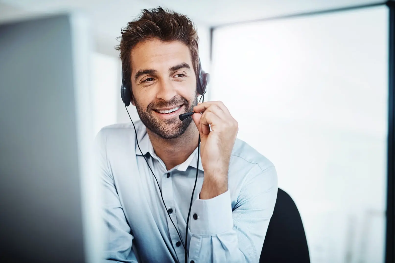 A customer support representative eagerly helping a customer via a call on his headset.