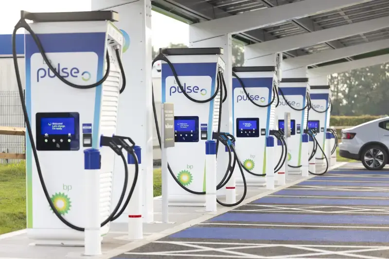 A photo of several bp pulse charging bays next to each other. In the background a silver car is being charged