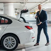 junger Mann in der Tiefgarage stellt seine Aktentasche in den geöffneten Kofferraum seines Autos