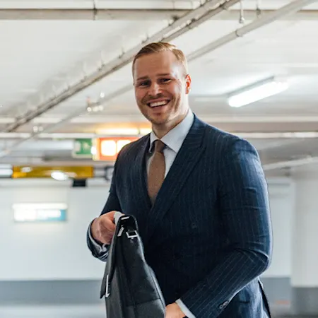 junger Mann in der Tiefgarage stellt seine Aktentasche in den geöffneten Kofferraum seines Autos