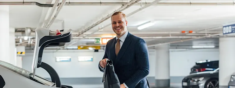junger Mann in der Tiefgarage stellt seine Aktentasche in den geöffneten Kofferraum seines Autos