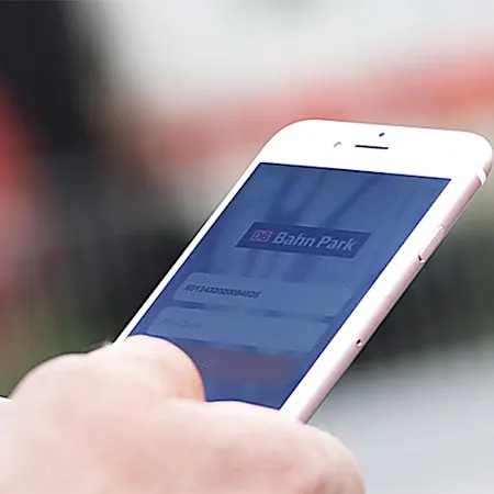 Mann mit Smartphone in der Hand steht vor einem Zug