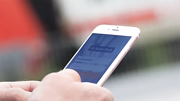Mann mit Smartphone in der Hand steht vor einem Zug