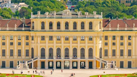 Parken in Wien: Das Schloss Schönbrunn erstreckt sich im Vordergrund des Bildes hinter ihr ist die Stadt Wien zu sehen.