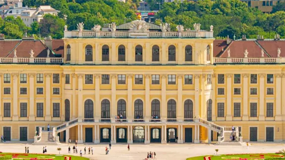 Parken in Wien: Das Schloss Schönbrunn erstreckt sich im Vordergrund des Bildes hinter ihr ist die Stadt Wien zu sehen.
