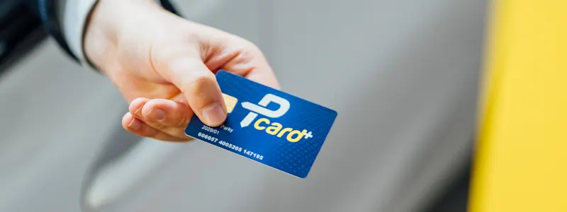 Arm am Fenster eines Autos hält die Pcard in der Hand