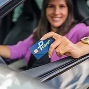junge Frau im Auto am Steuer hält die Kundenkarte Pcard in der Hand aus dem Fenster