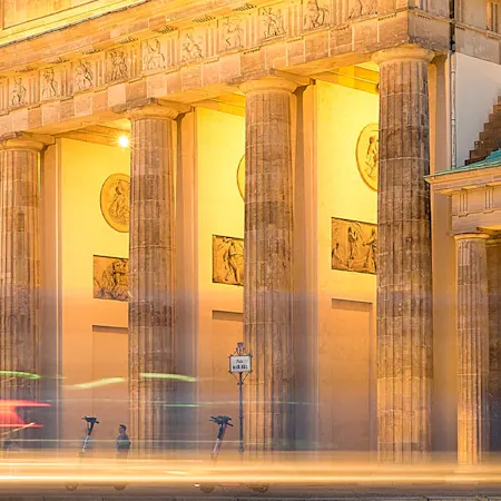 nächtliche, beleuchtete Straße auf das Berliner Brandenburger Tor hinführend