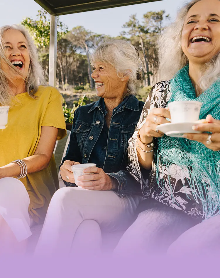 Drei lächelnde Frauen mittleren Alters trinken Tee