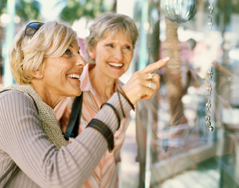 Glücklich aufgeregte Frauen mittleren Alters betrachten Etwas im Schaufenster