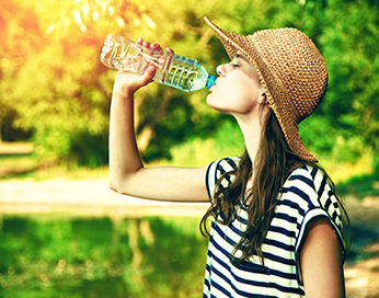 Junge Frau trinkt Wasser aus einer Flasche