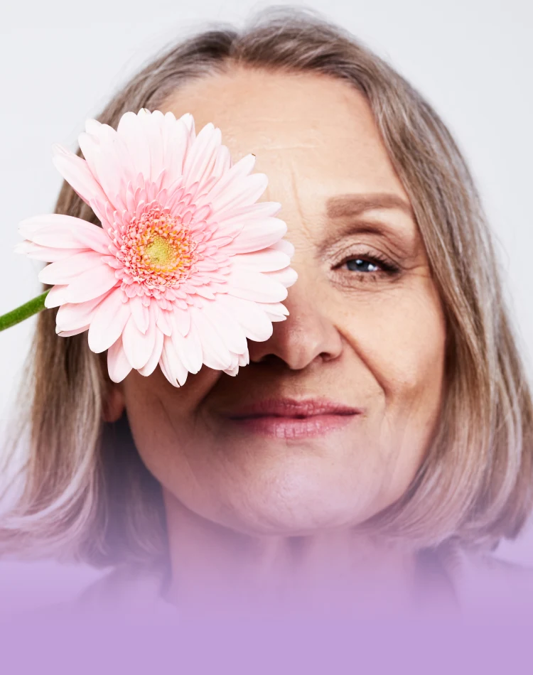 Eine Frau mittleren Alters bedeckt ihr Auge mit rosa Blume
