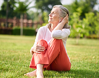 Frau mittleren Alters sitzt auf dem Gras