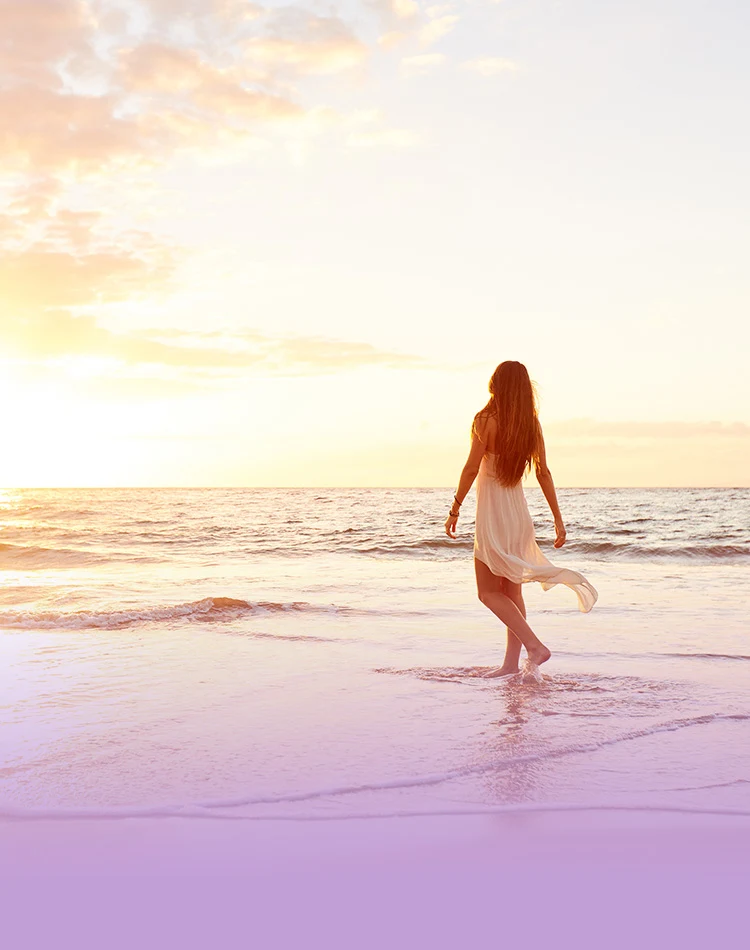 Eine Frau taucht ihre Füße während eines Spaziergangs am Strand ins Wasser.