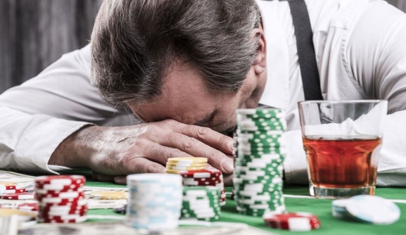 A desperate man losing money playing a card game at the gambling table.
