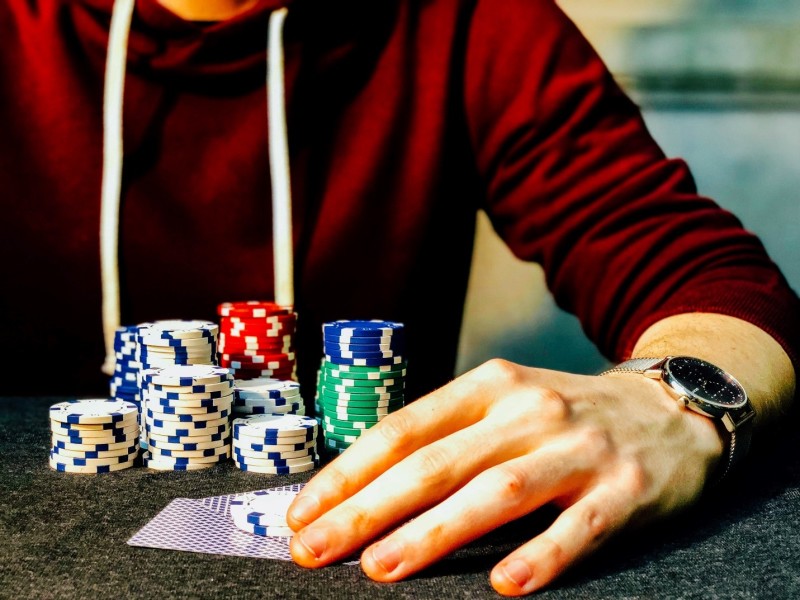 Player’s hand on cards and chips at the gambling table.