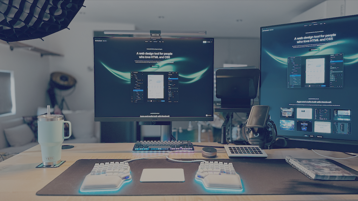 A photo of my desk. My Dygma Defy keyboard is set up right in front of the BenQ monitor, which is directly in front of where I sit. To the right of that is my camera with an Elgato Prompter attached to it. To the right of that is the LG DualUp monitor. My microphone is placed in front of the camera. There's also various other things on the desk including a turquoise Yeti cup, a note book, and an Elgat stream deck.
