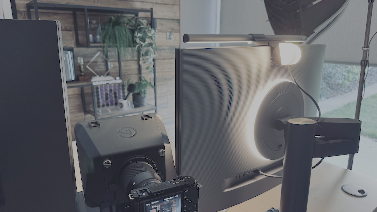 A photo of the BenQ monitor from the back with the Moon Halo lit up. The BenQ screenbar halo is also placed on the top of the monitor, with the back portion lit up.