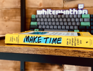 The Make Time book, laying on my shelf, with a keyboard and my whitep4nth3r 3D logo behind it, slightly out of focus.