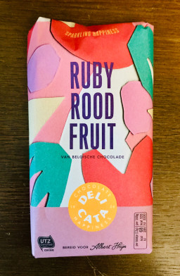 A chocolate bar called "ruby rood fruit", with packaging that boasts cut-paper abstract shapes in pink, red, and green.