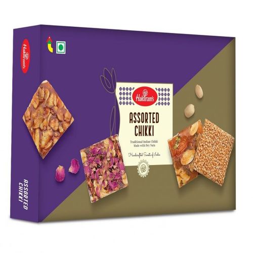 A purple box of assorted chikki, which are squares that look a lot like peanut brittle
