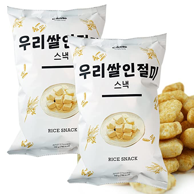 Two bags labeled "rice snack" with a pile of cubes stacked on a plate on the bags. Behind the bags are a pile of the individual rice snacks.