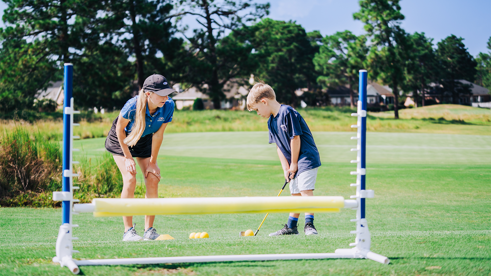 A youth golfer works on a fun drill with their coach. 