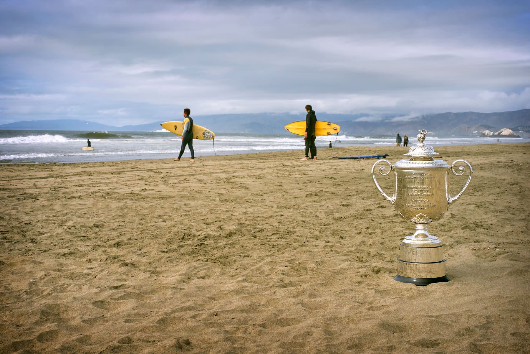 The Wanamaker Trophy sits on the beach as surfers head out to ride the waves of the Pacific Ocean.