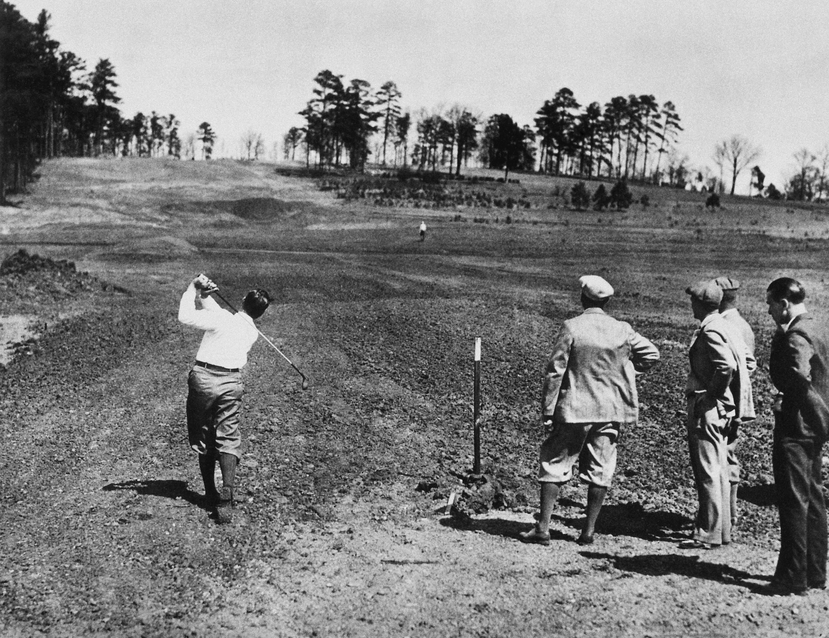 Bobby Jones plays a shot on Augusta National's eighth hole while the course in under construction in 1932, with his father, Bob Jones, Sr. (Colonel), Clifford Roberts, and Alister MacKenzie watching. (Photo by Augusta National/Getty Images)