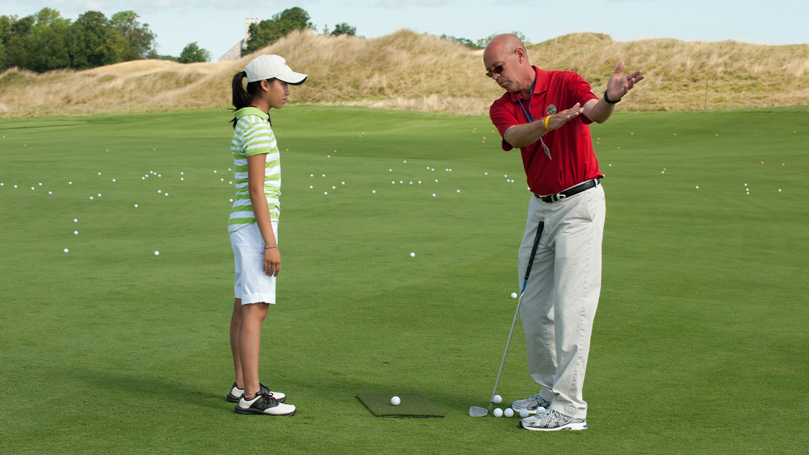 A Wisconsin Section PGA Professional works with a junior golfer on her form during a youth clinic. (Photo by Montana Pritchard/The PGA of America)