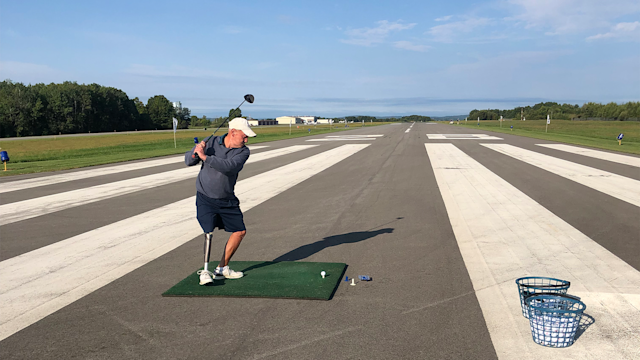 A participant hits his drive down the runway. 